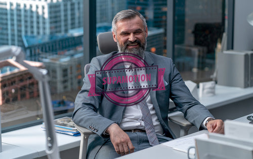 Portrait of 50s Caucasian businessman CEO posing at his desk in modern office