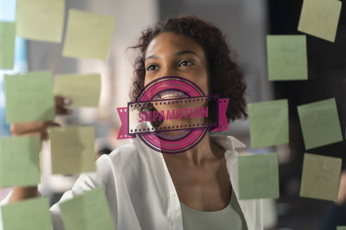 Young African American female employee looking at adhesive sticky notes