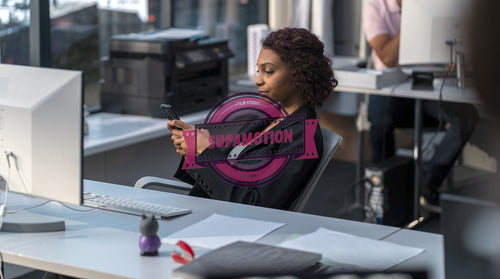 African American female employee using her smartphone at her desk