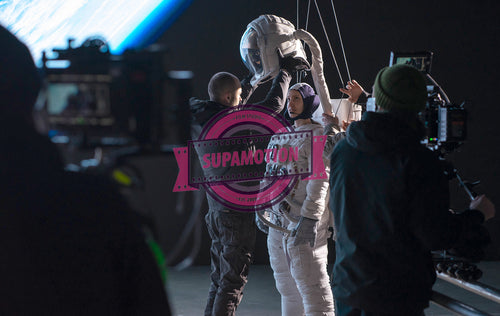 Caucasian female stuntwoman wearing a spacesuit being prepared for the shot