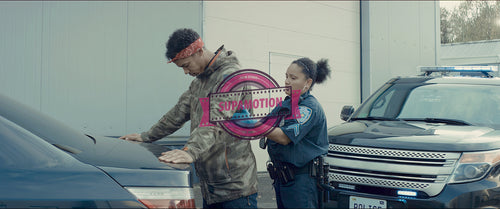 Police officer searches a suspect near a police vehicle in the street