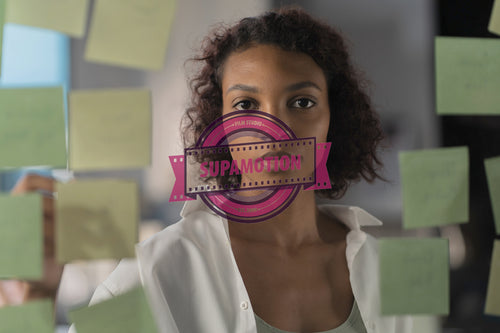 Young African American female employee looking at adhesive sticky notes