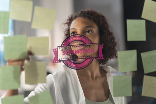 Young African American female employee looking at adhesive sticky notes