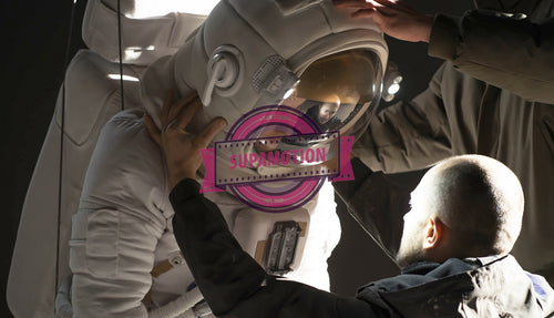 Caucasian female stuntwoman wearing a spacesuit being prepared for the shot