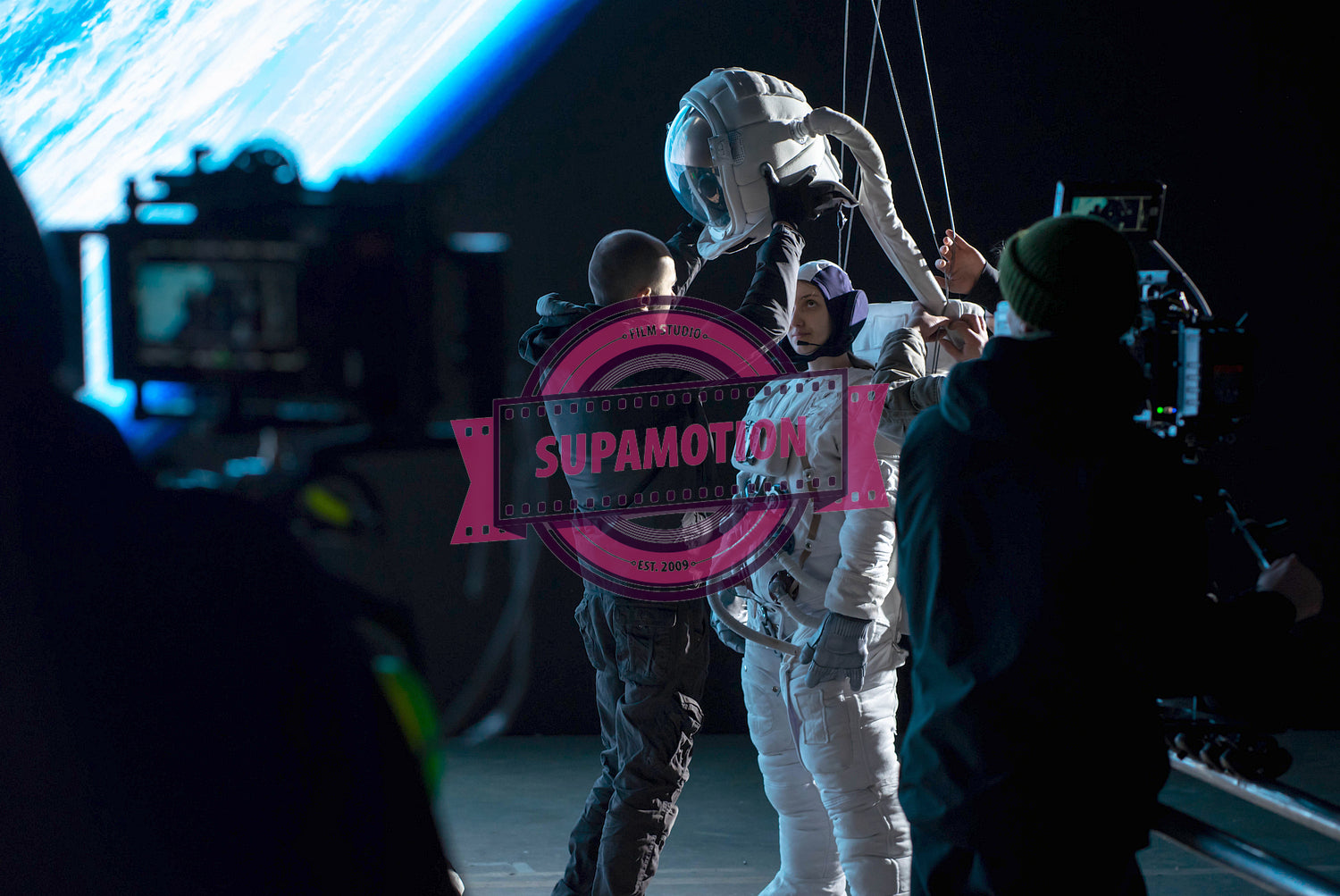 Caucasian female stuntwoman wearing a spacesuit being prepared for the shot