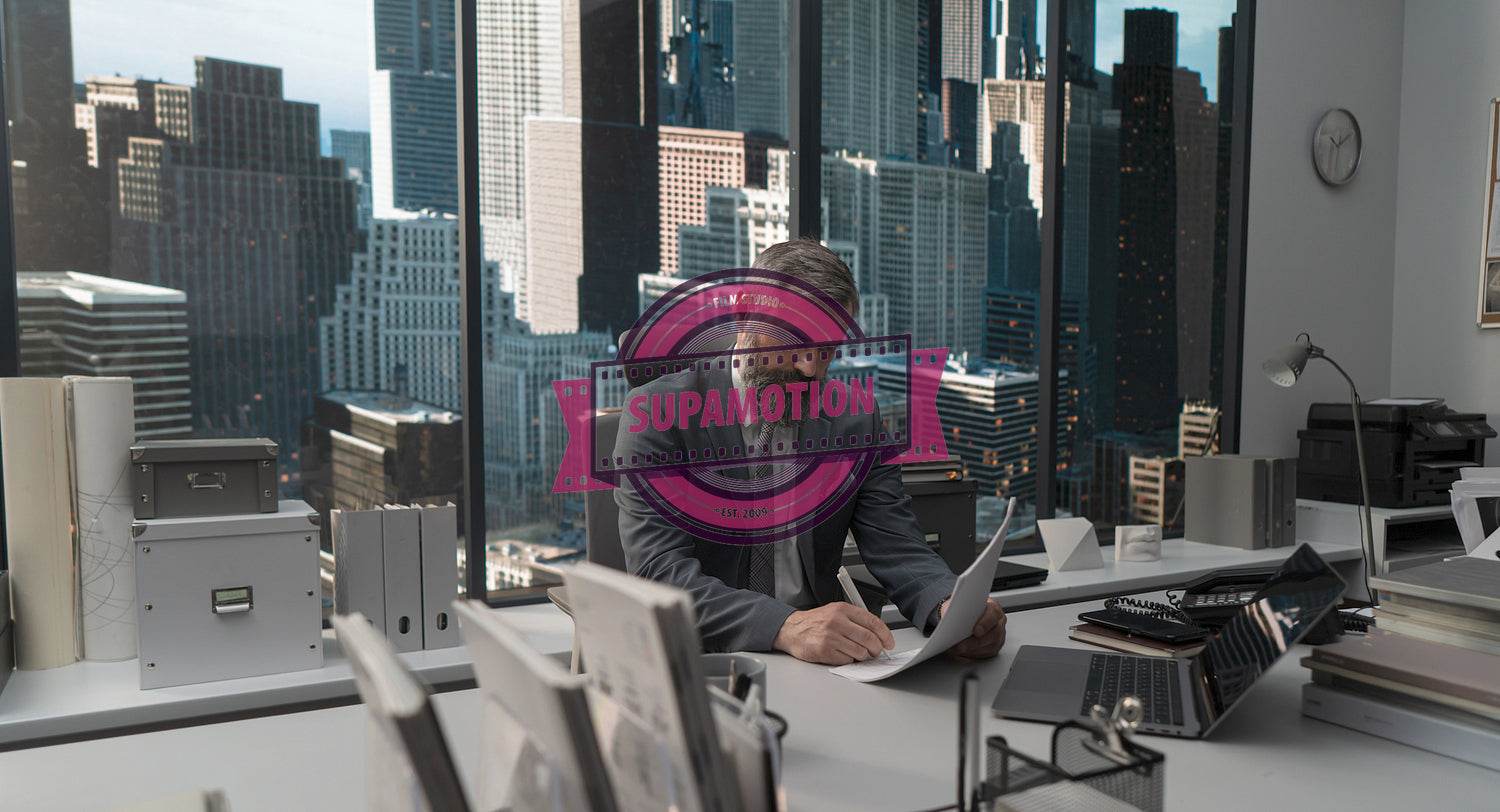 Portrait of 50s adult Caucasian businessman signing documents in his office 