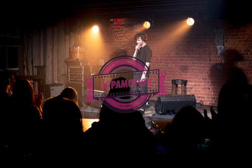 Young Caucasian male comedian performing his stand-up monologue on a stage of a small venue