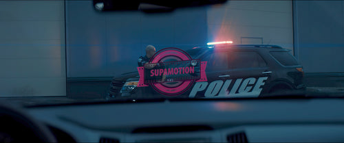 Caucasian male police officer standing guard in the street near police car